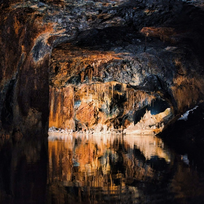 Cave with water reflecting colorful mineral deposits